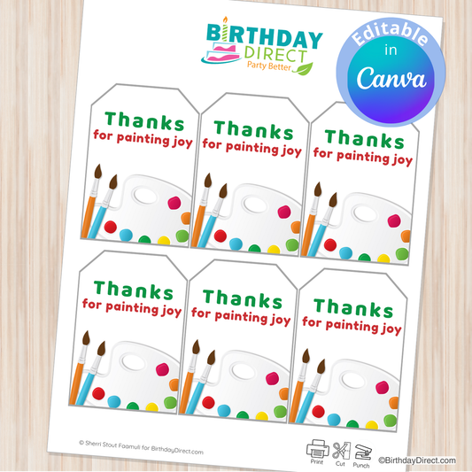 Sheet of printable tags with paintbrushes and text 'Thanks for painting joy' from Birthday Direct on a wooden surface.