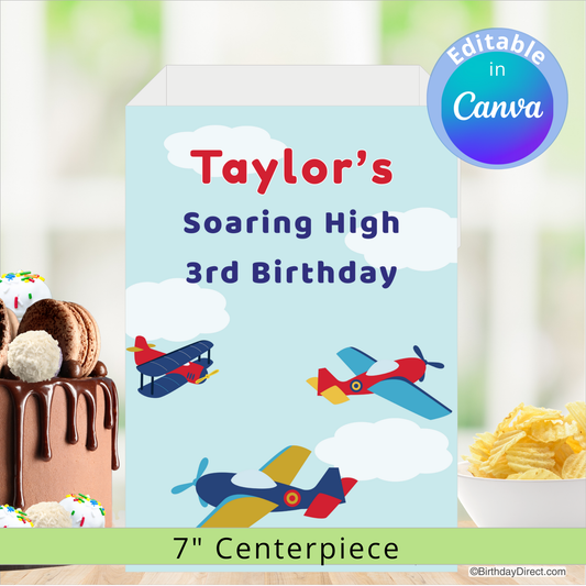 Personalized birthday centerpiece with airplane design and text 'Taylor's Soaring High 3rd Birthday' on a blurred background of cake and snacks.