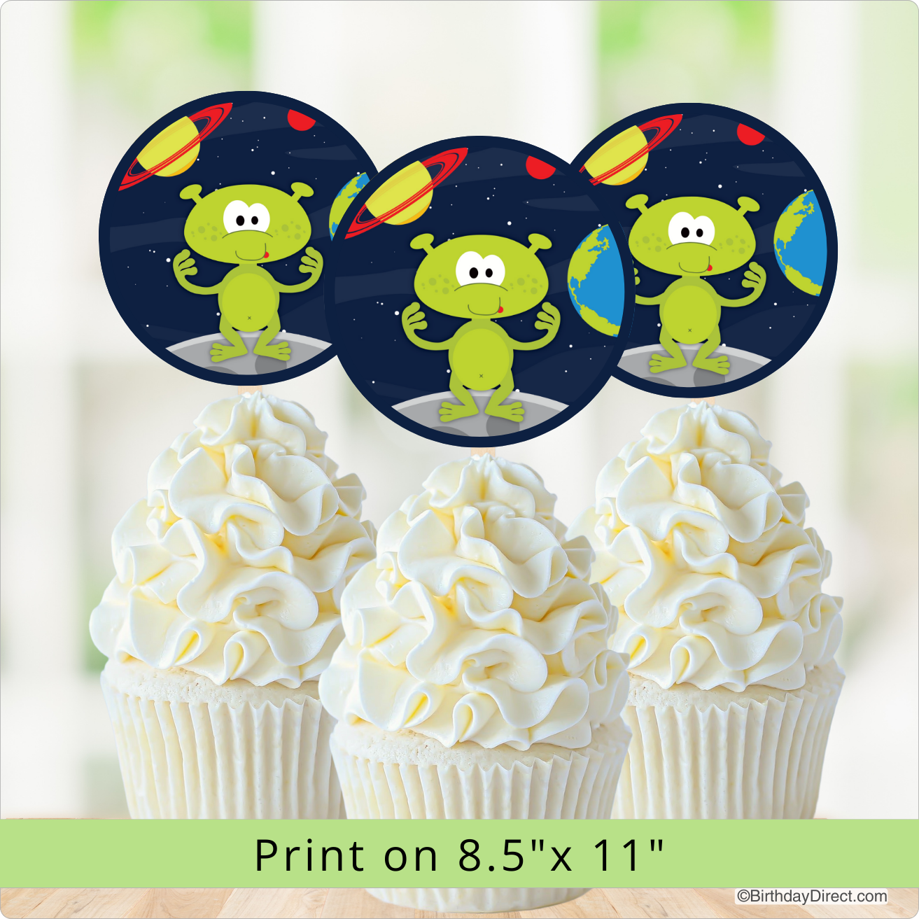 Alien-themed cupcake toppers with a space background on top of white cupcakes.
